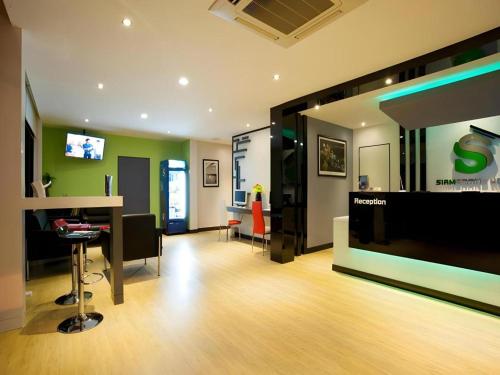 a living room with a tv and a table and a bar at Siamgrand Hotel in Nakhon Phanom