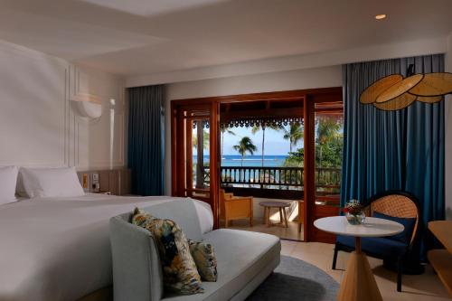 a hotel room with a bed and a balcony with the ocean at Sofitel Mauritius L'Imperial Resort & Spa in Flic-en-Flac
