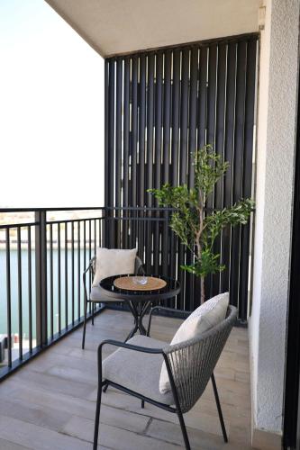 a balcony with two chairs and a table and a tree at Yas Island 2BR Luxury Apartment by Ferrari World in Abu Dhabi
