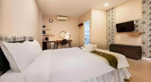 a bedroom with a large white bed and a desk at The Loom Rangsit in Pathum Thani