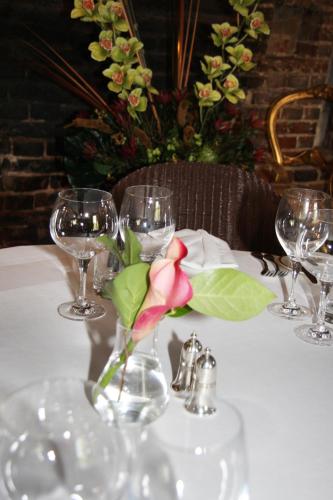 a table with wine glasses and a flower in a vase at The White Hart in Great Yeldham