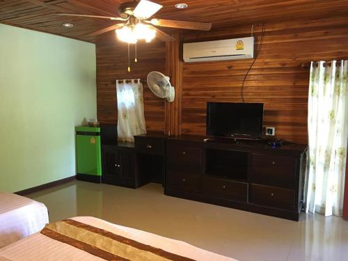 a bedroom with a bed and a tv and a fan at Ban Noi Resort Phrae in Phrae