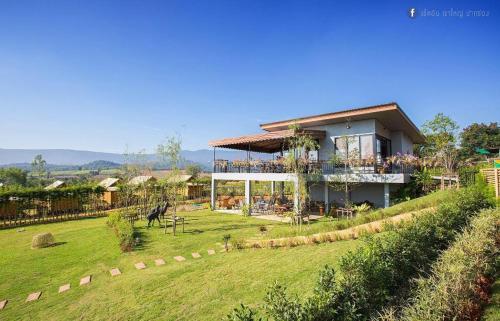 ein Haus mit einer großen Wiese davor in der Unterkunft Baansuanpai Noppakao in Mu Si