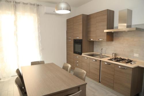 a kitchen with wooden cabinets and a table with chairs at B&B Mimì in Castelsardo
