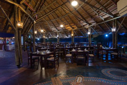 una sala da pranzo con tavoli, sedie e luci di Azambezi River Lodge a Victoria Falls