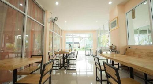 a restaurant with wooden tables and chairs and windows at Bees Smile Hotel in Chiang Rai