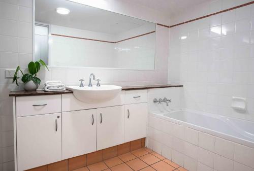 a white bathroom with a sink and a tub at Nautilus 1 - 1- 46 Lawson Street in Byron Bay