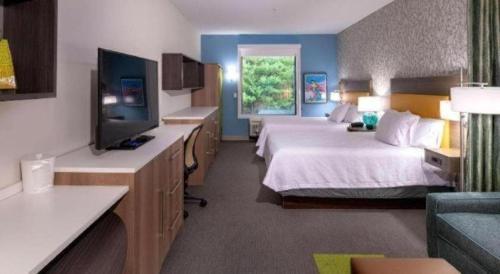 a hotel room with two beds and a flat screen tv at Home2 Suites by Hilton Raynham Taunton in Raynham