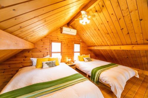 two beds in a log cabin with wooden ceilings at [Sumoto City] Log house Gosyokumachi1 - Vacation STAY 14162 in Sumoto