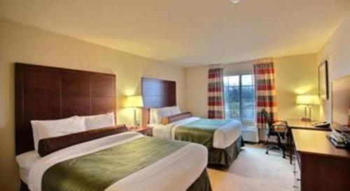 a hotel room with two beds and a desk at AmericInn by Wyndham Oshkosh in Oshkosh