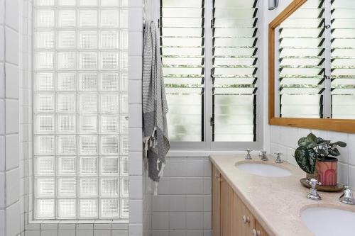 a bathroom with a sink and a shower with windows at Belongil Summerhouse 12 Childe Street in Byron Bay