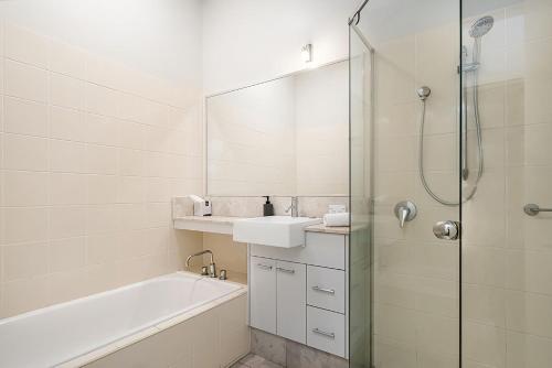 a bathroom with a tub and a sink and a shower at Pipi's On The Beach 1 - 2 Fletcher Street in Byron Bay