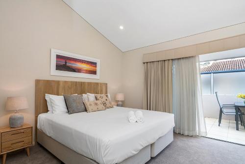 a bedroom with a large white bed and a balcony at Pipi's On The Beach 1 - 2 Fletcher Street in Byron Bay