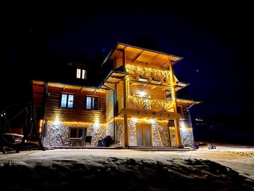 a wooden house with lights on it at night at Żaroowka Slow House in Międzybrodzie Żywieckie