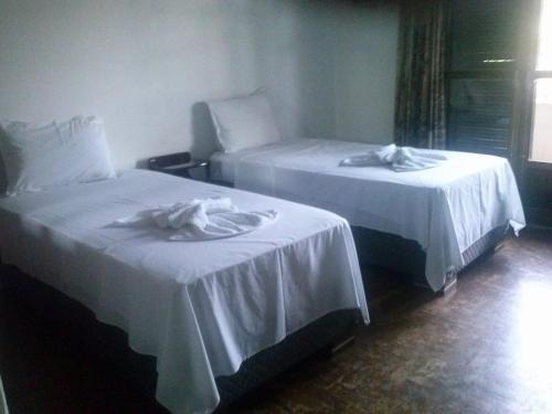 two beds in a hotel room with white sheets at Ouro Preto Hotel in Restinga Sêca