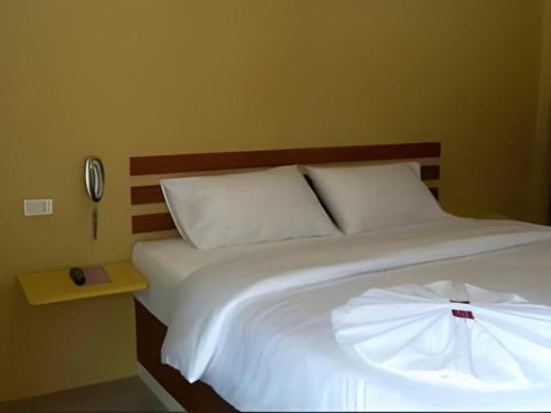 a bed with white sheets and a clock on a wall at UII Boutique Place in Sakon Nakhon