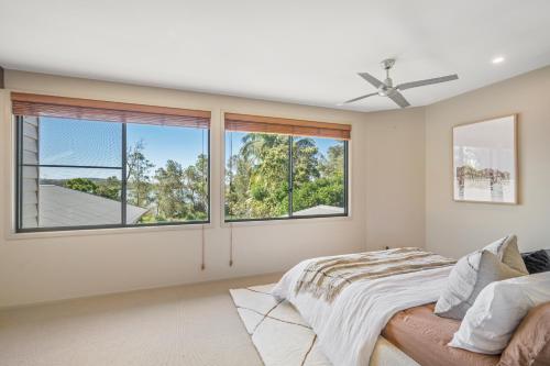 a bedroom with windows and a bed and a ceiling fan at Lakeside Bliss in Dunbogan