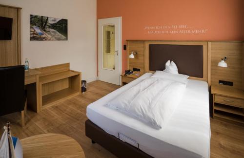 a bedroom with a large white bed and a desk at Alpenstadthotels in Bad Reichenhall