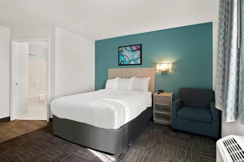 a hotel room with a bed and a chair at MainStay Suites Cincinnati Blue Ash in Blue Ash