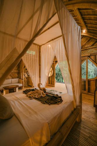 a large bed in a tent with curtains at Asvara Eco Bali Bamboo House in Sidemen