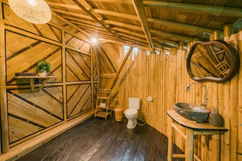 a bathroom with a sink and a toilet in a wooden room at Asvara Eco Bali Bamboo House in Sidemen