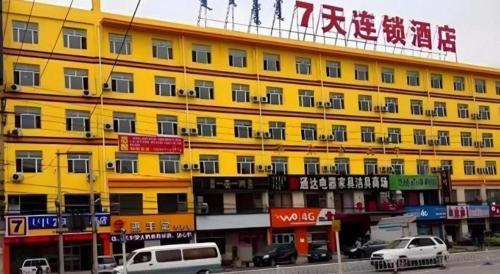 a yellow building with cars parked in front of it at 7 Days Inn Hohhot Kaitai Market in Hohhot