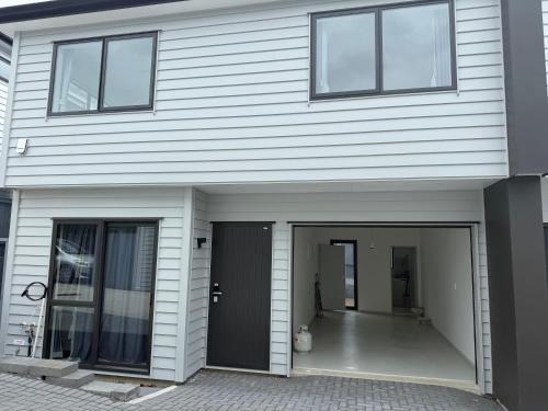 a white house with two windows and a door at 14C grove lane pakuranga in Auckland