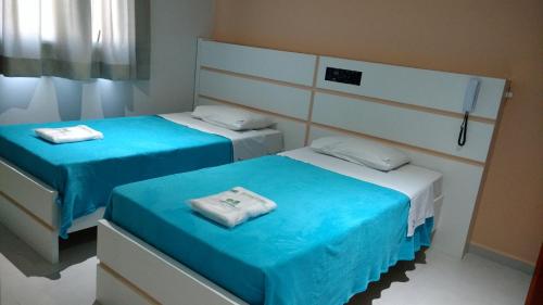 two beds in a room with blue and white at Lider Hotel in São Bernardo do Campo