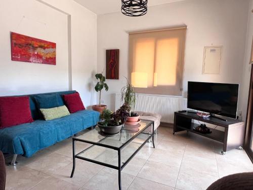 a living room with a blue couch and a tv at Villa Callione - Amazing view in Kyperounda