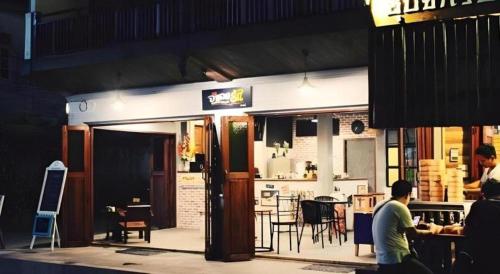 un homme debout à l'extérieur d'un restaurant avec une table dans l'établissement Remember Loei Love, à Chiang Khan