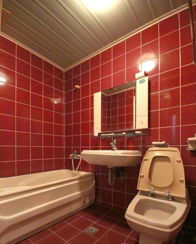 une salle de bain carrelée rouge avec toilettes et lavabo dans l'établissement Broadway Hotel, à Taichung