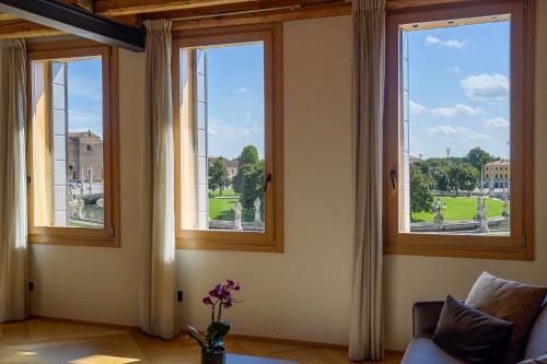 a living room with three windows and a couch at Palazzo CarpeDiem-Prato della Valle in Padova