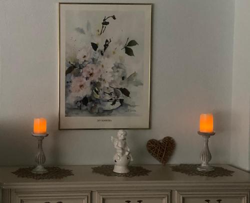 a picture on the wall above a dresser with two candles at Große Helle Wohnung am Wald in Bad Saarow Nahe Grünheide und Berlin Souterrain in Bad Saarow