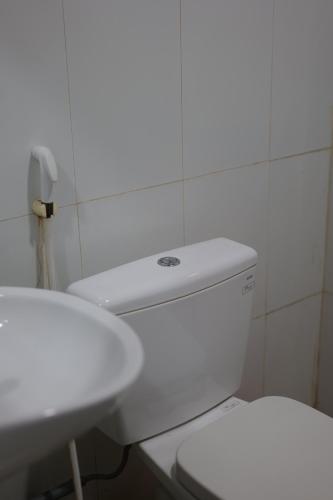 a bathroom with a white toilet and a sink at Nông Trại Hải Vân - Sân Chim Vàm Hồ in Ben Tre