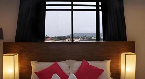 a bed with two red pillows and a large window at Iroom Hotel in Surat Thani
