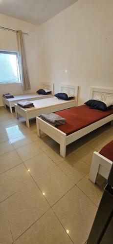 a room with three beds in a room with a window at Sheeva Backpacker Hostel in Abu Dhabi