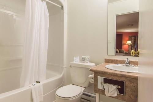 a white bathroom with a toilet and a sink at Rodeway Inn King William in Huntsville