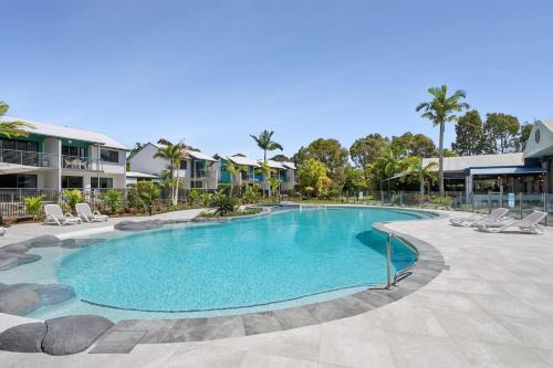 a swimming pool at a resort with lounge chairs at Sun Drenched Unit in Noosaville in Noosaville