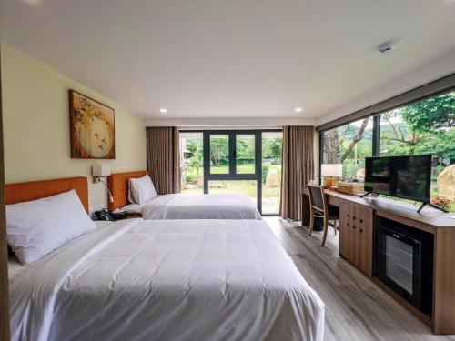 a bedroom with two beds and a desk and a television at Lâm Viên Hotel & Retreat in Kon Rung (1)