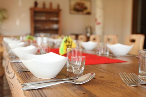 a long wooden table with white bowls and silverware at Willa Czarownica in Nowa Słupia