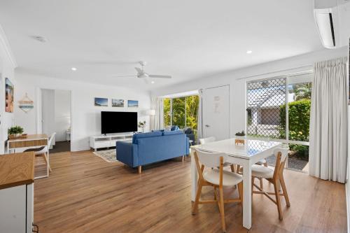 a living room with a table and a blue couch at 2 Bedroom Ground Level Villa in Tropical 4* Resort in Noosaville