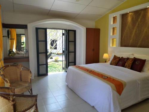 una camera da letto con un grande letto bianco e una sedia di Aquarius Resort a Marawila