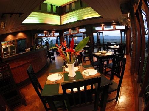 a dining room with tables and chairs in a restaurant at Thaton Hill Resort in Mae Ai