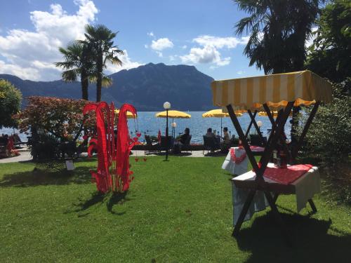 a park with a table and an umbrella and the water at Hotel Beau Rivage Weggis in Weggis
