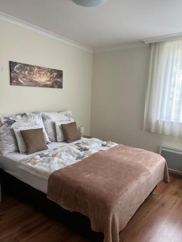 a white bedroom with a large bed with pillows at Viva Apartman in Nyíregyháza