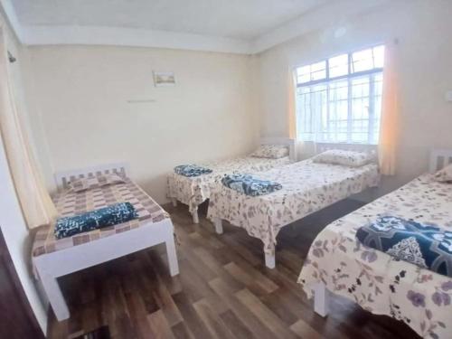 a bedroom with three beds and a window at Siej Homestay in Cherrapunji
