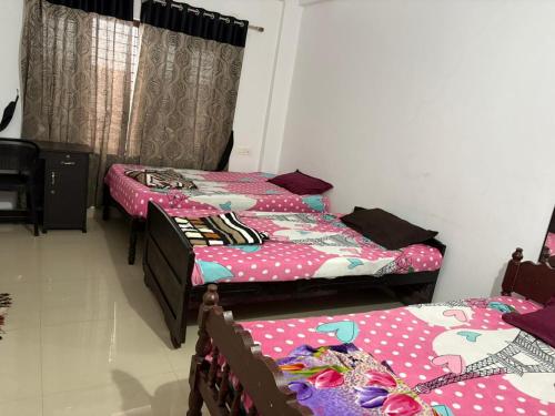 2 Betten in einem Zimmer mit Polka-Punkten in der Unterkunft HR Mukkali in Attappādi