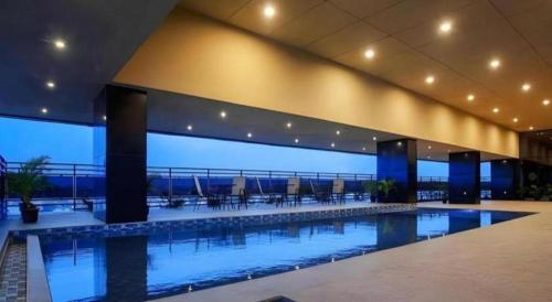a large swimming pool in a building with tables and chairs at The Bono Hotel Pekanbaru in Pekanbaru