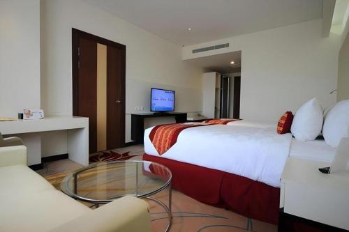 a hotel room with two beds and a glass table at G'Sign Hotel Banjarmasin in Banjarmasin