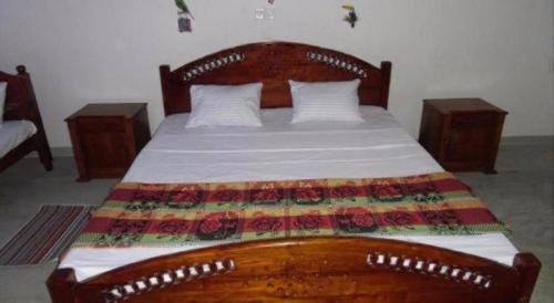 a bedroom with a wooden bed with a wooden headboard and two tables at Lagoon Beach Resort in Tangalle